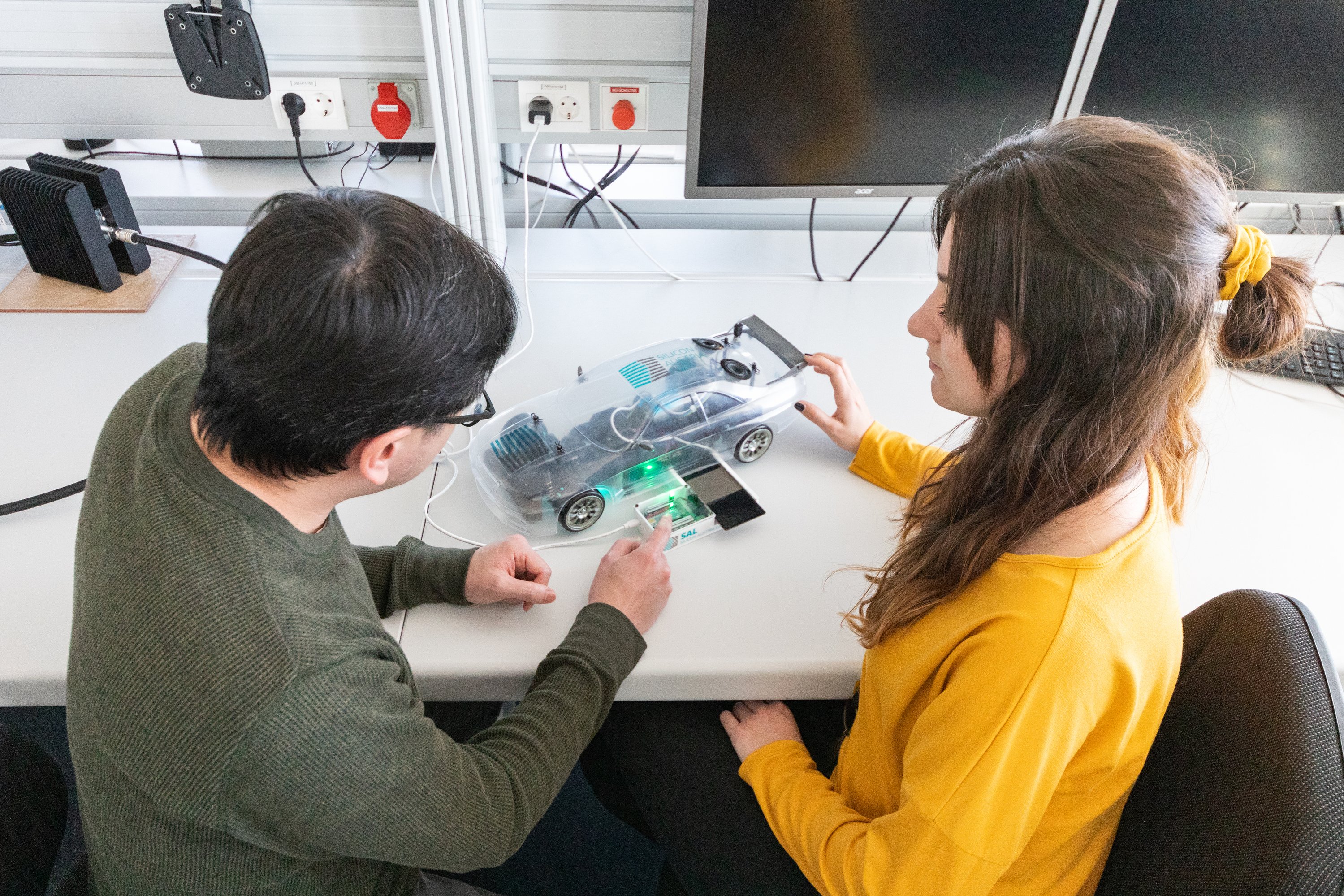 two people looking at a miniaturized model e-car
