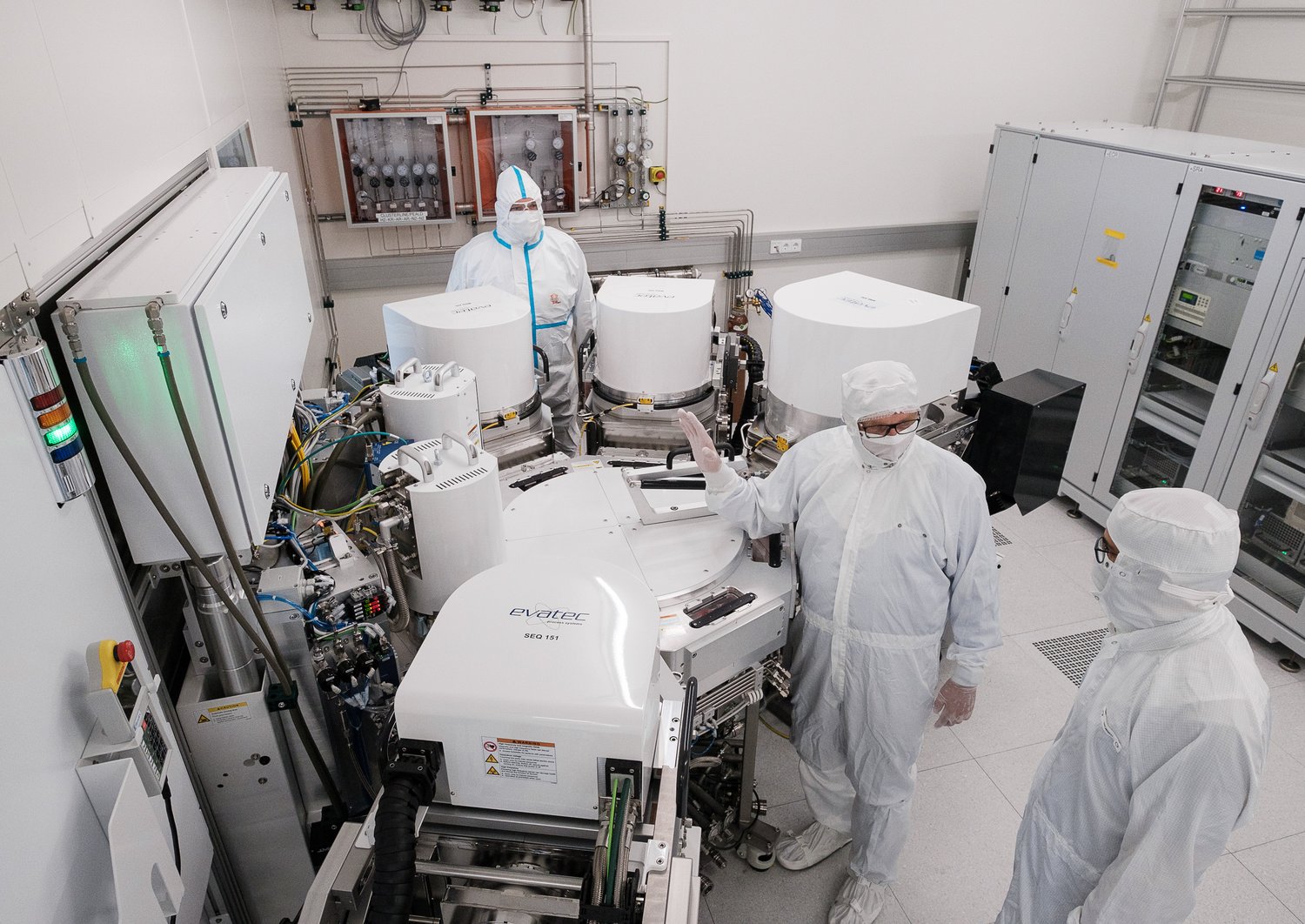 Mehrere Forscher die in einem Clean Room um ein Clustertool stehen