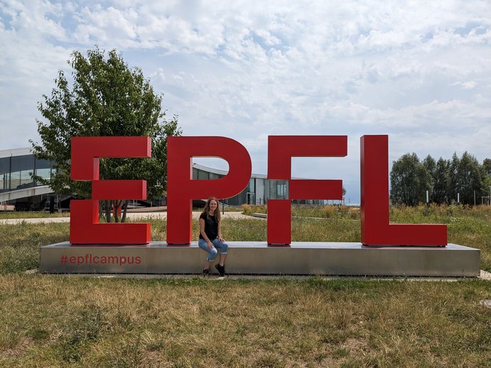 Blonde Frau vor dem physischen Logo der EPFL