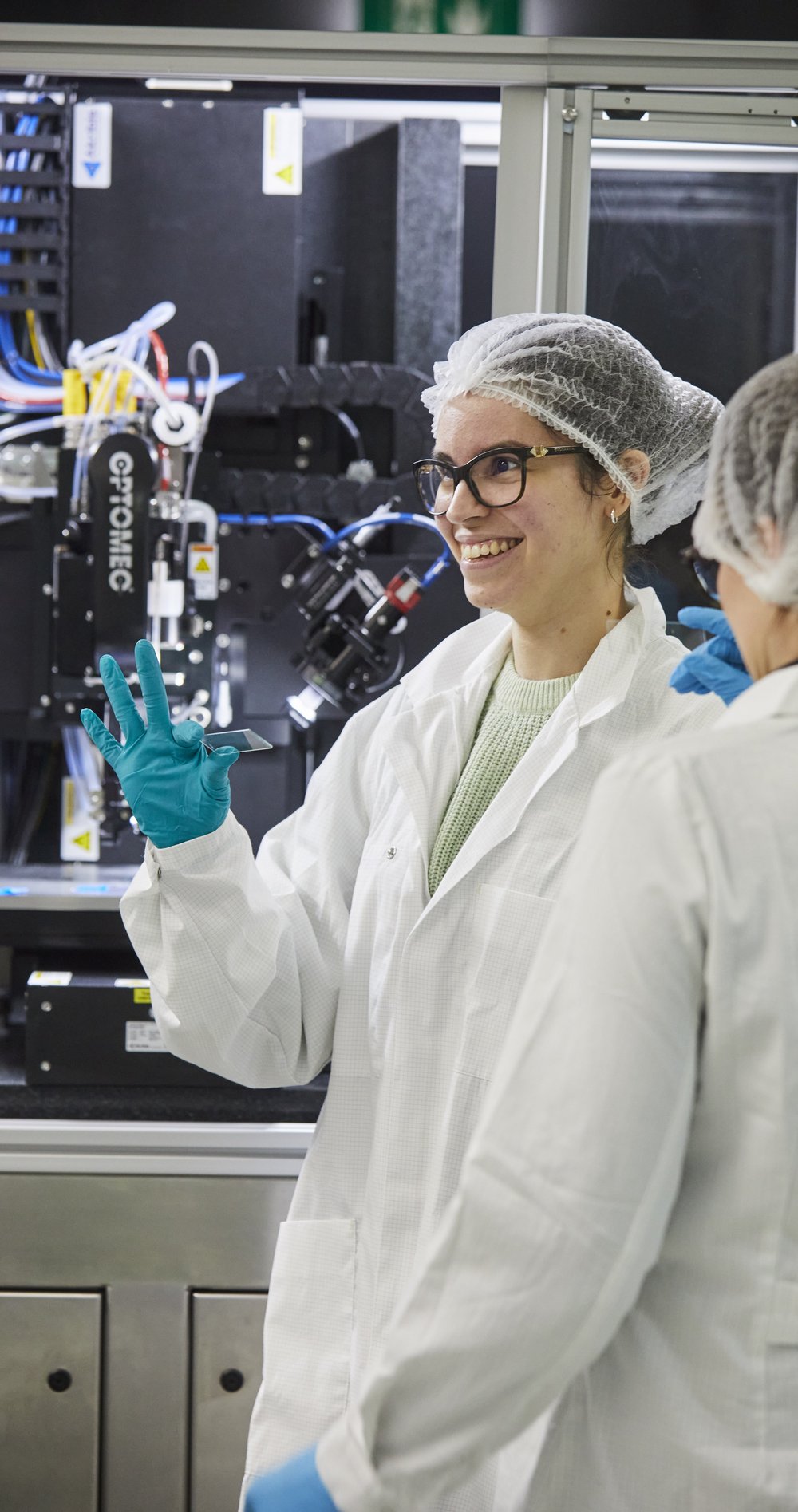 Emily Bezerra in Schutzkleidung im Labor lacht in die Kamera