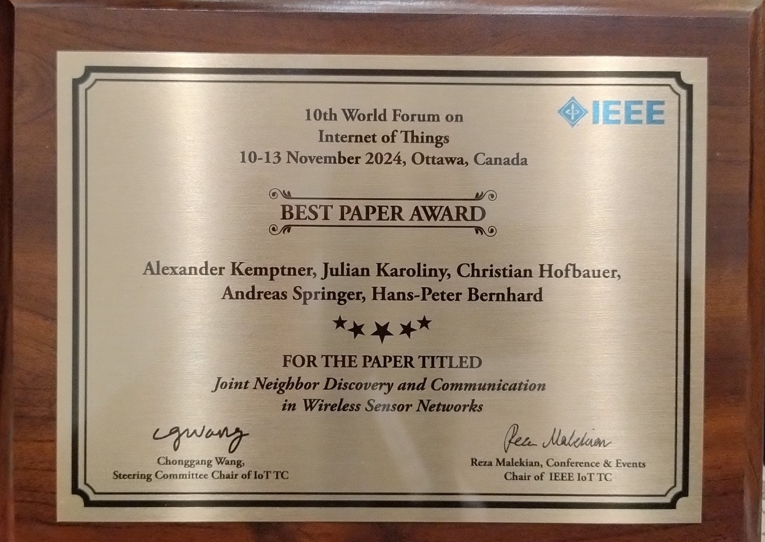 Metallplakette mit der Schrift "Best Paper Award" und den Namen und dem Titel des Papers. 