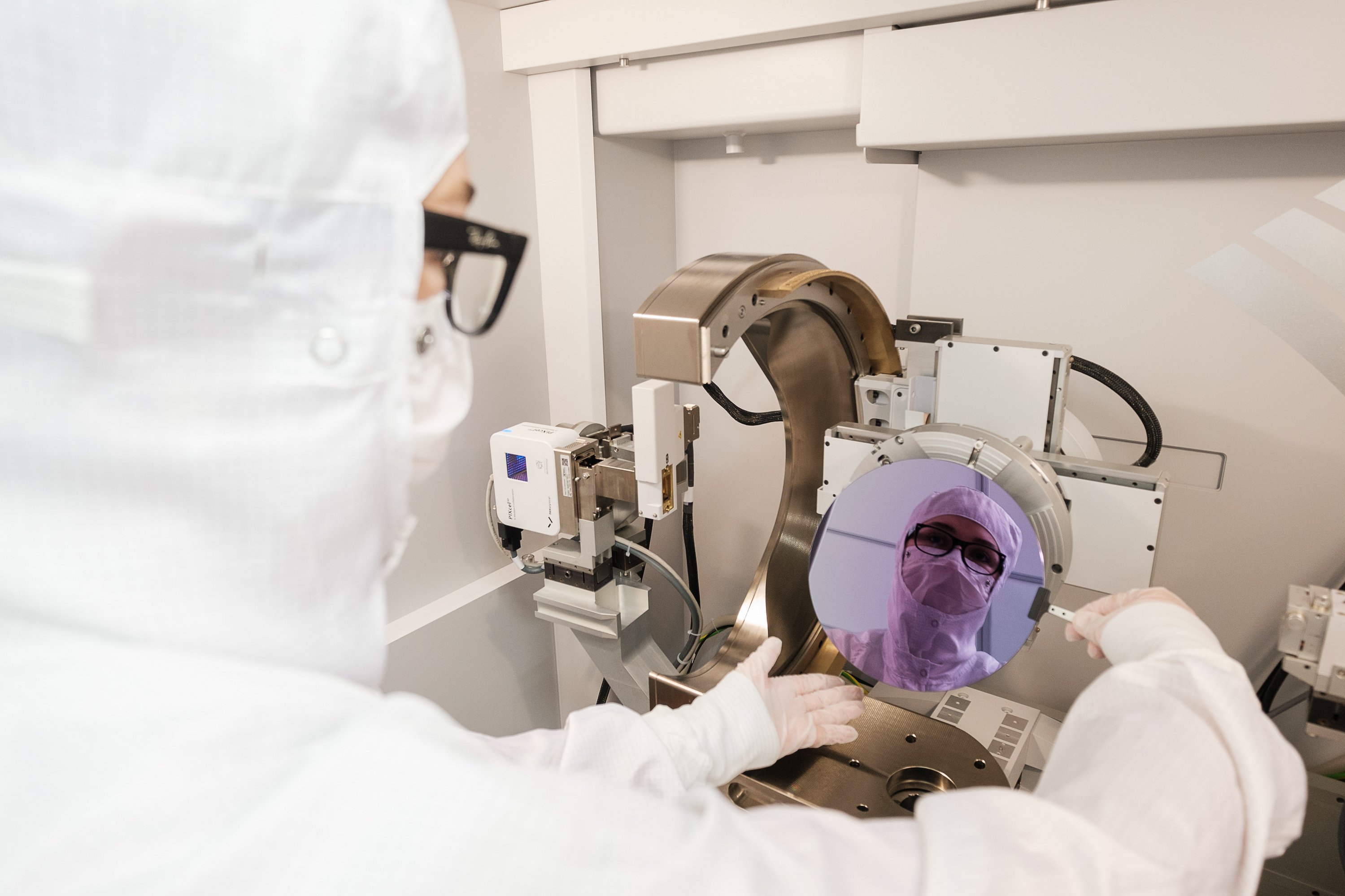 Madeleine in protective clothing in the cleanroom, holding a wafer. 