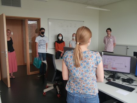 Four people standing in a room with a computer in it