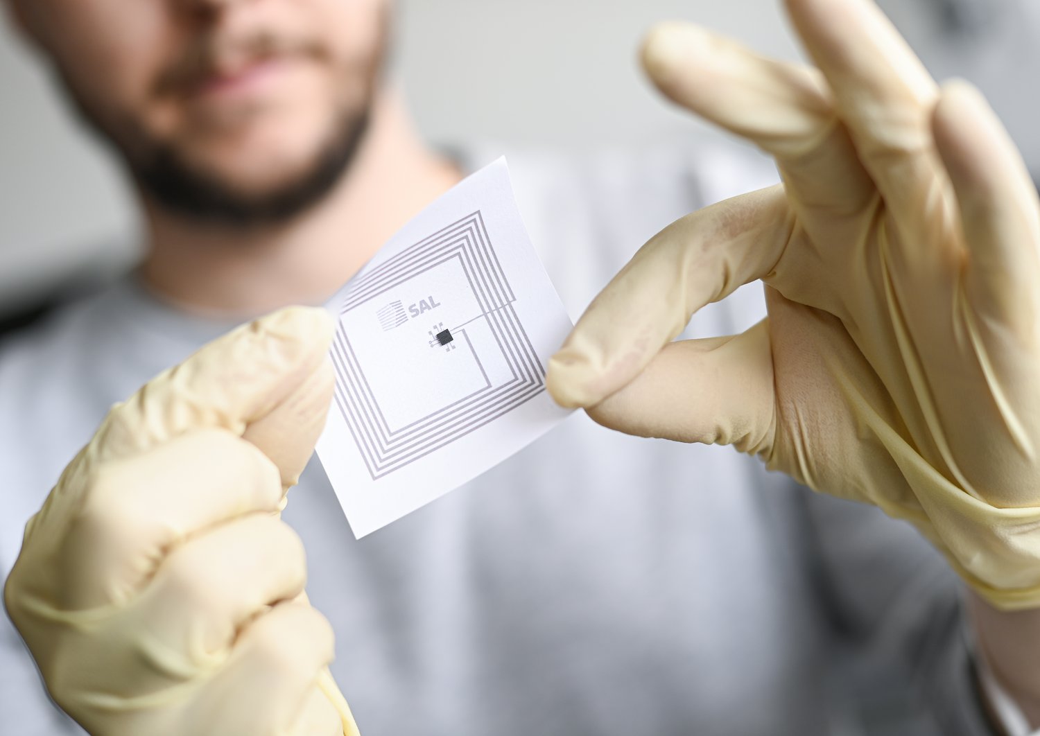 Ein Forscher hält einen gedruckten Sensor in der Hand