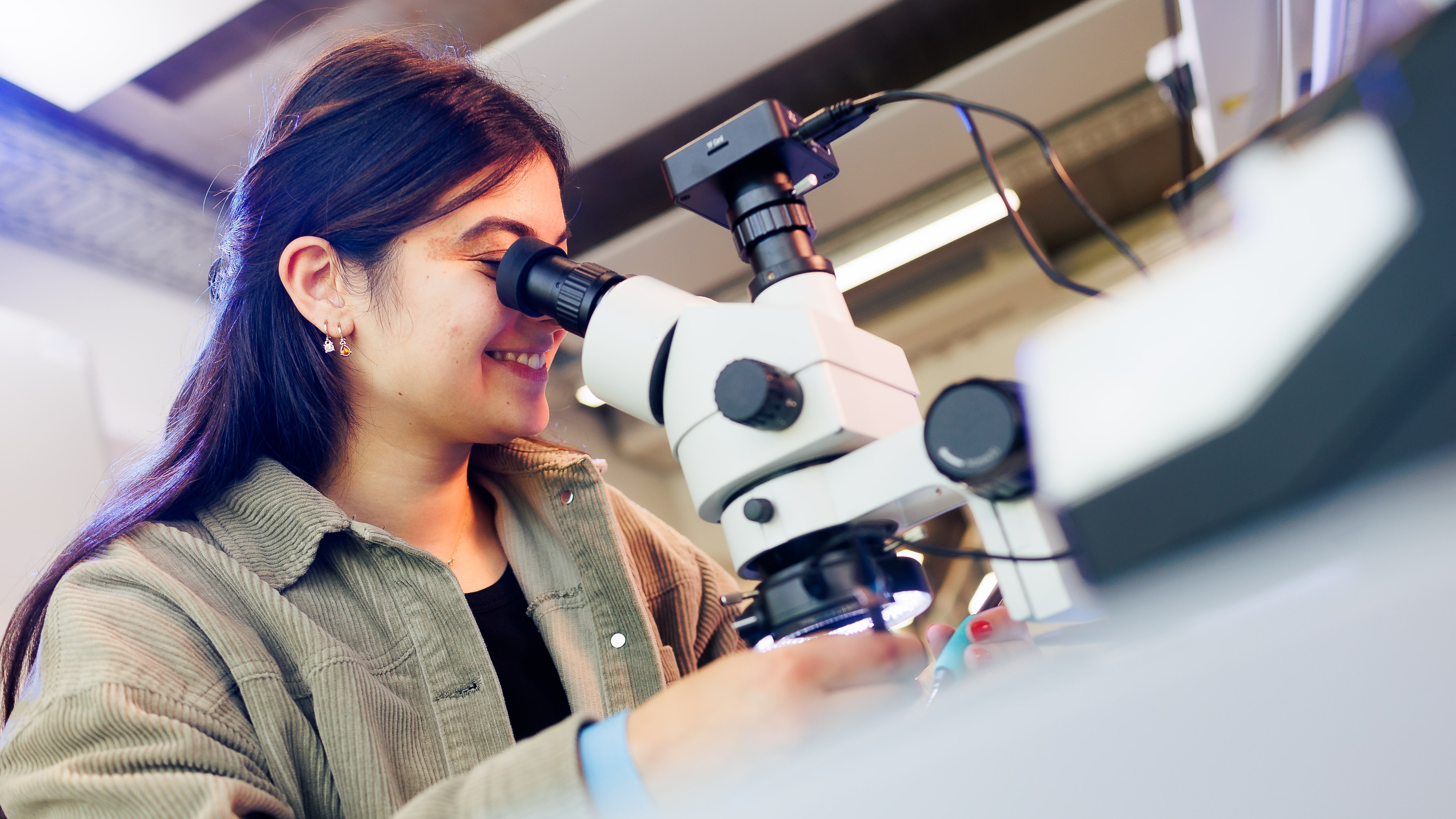 young woman looks at something under the microscope