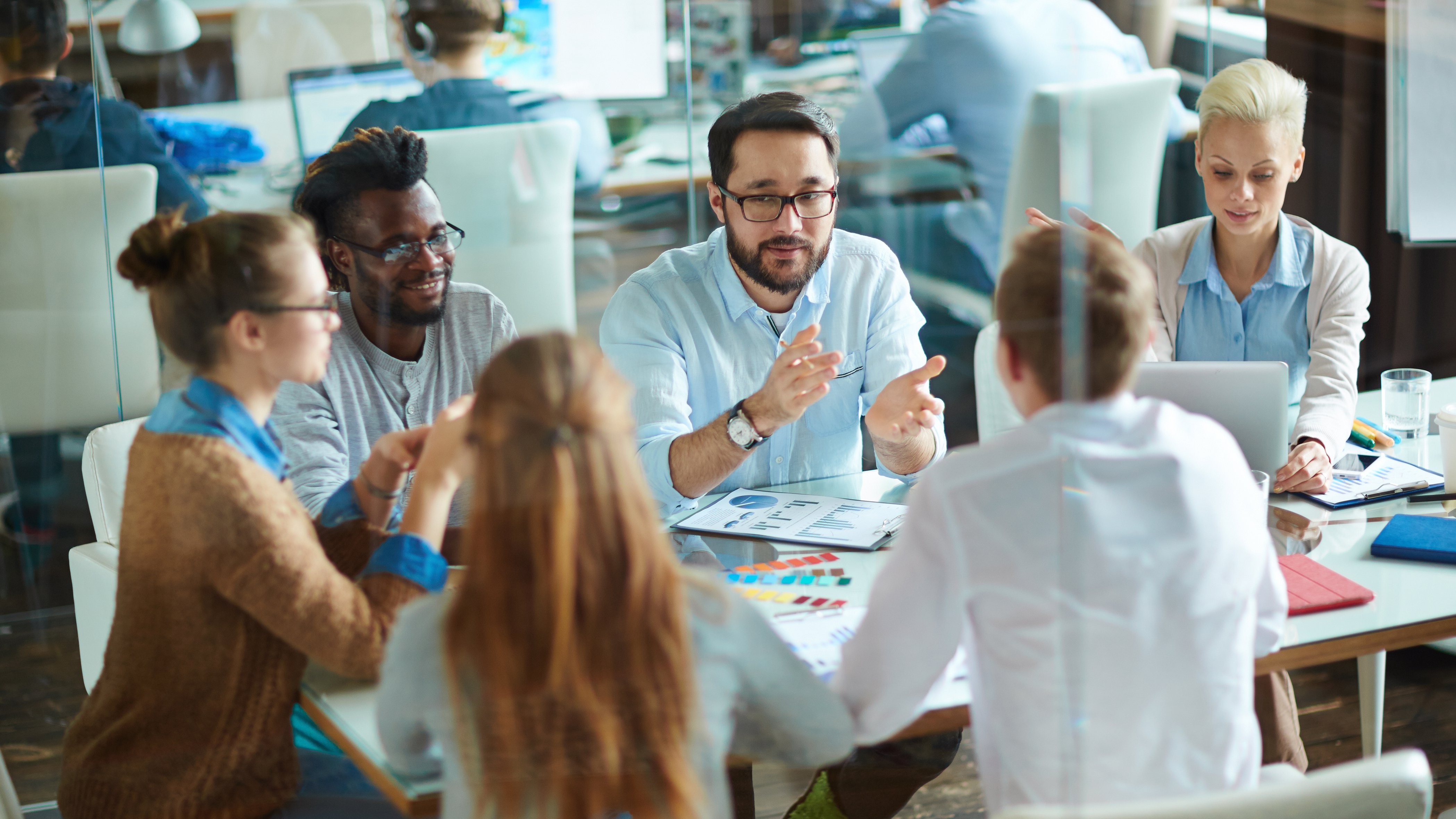 five people sit in an office and discuss something