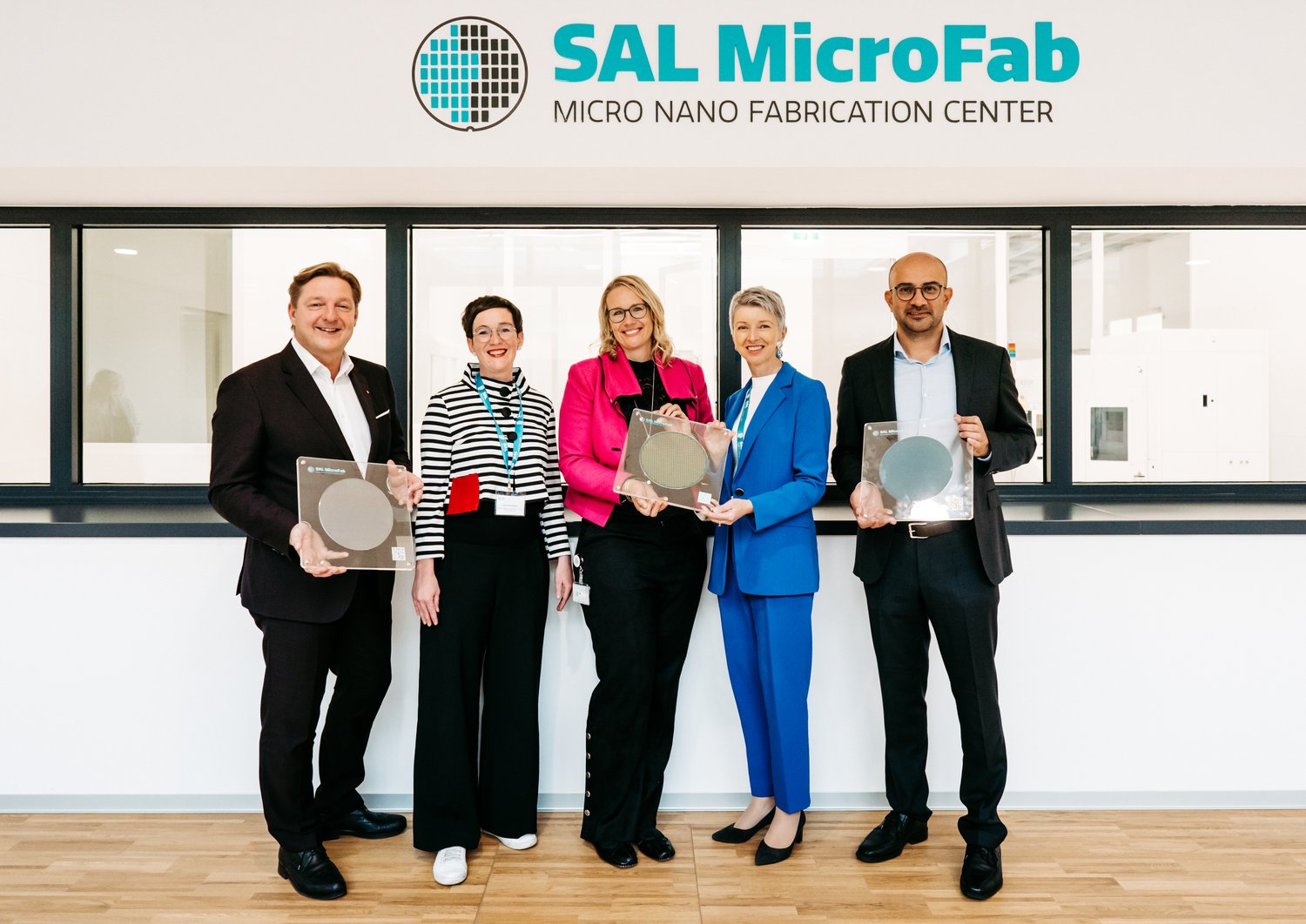 group picture with five people in business attire posing with wafers in their hands. f.l.t.r. Günther Albel (Mayor of Villach), Henriette Spyra (Head of Directorate General III for Innovation and Technology at the Ministry of Climate Action), Christina Hirschl (CEO of SAL), Gaby Schaunig (Deputy Governor Carinthia) und Mohssen Moridi (Head of Microsystems, SAL)