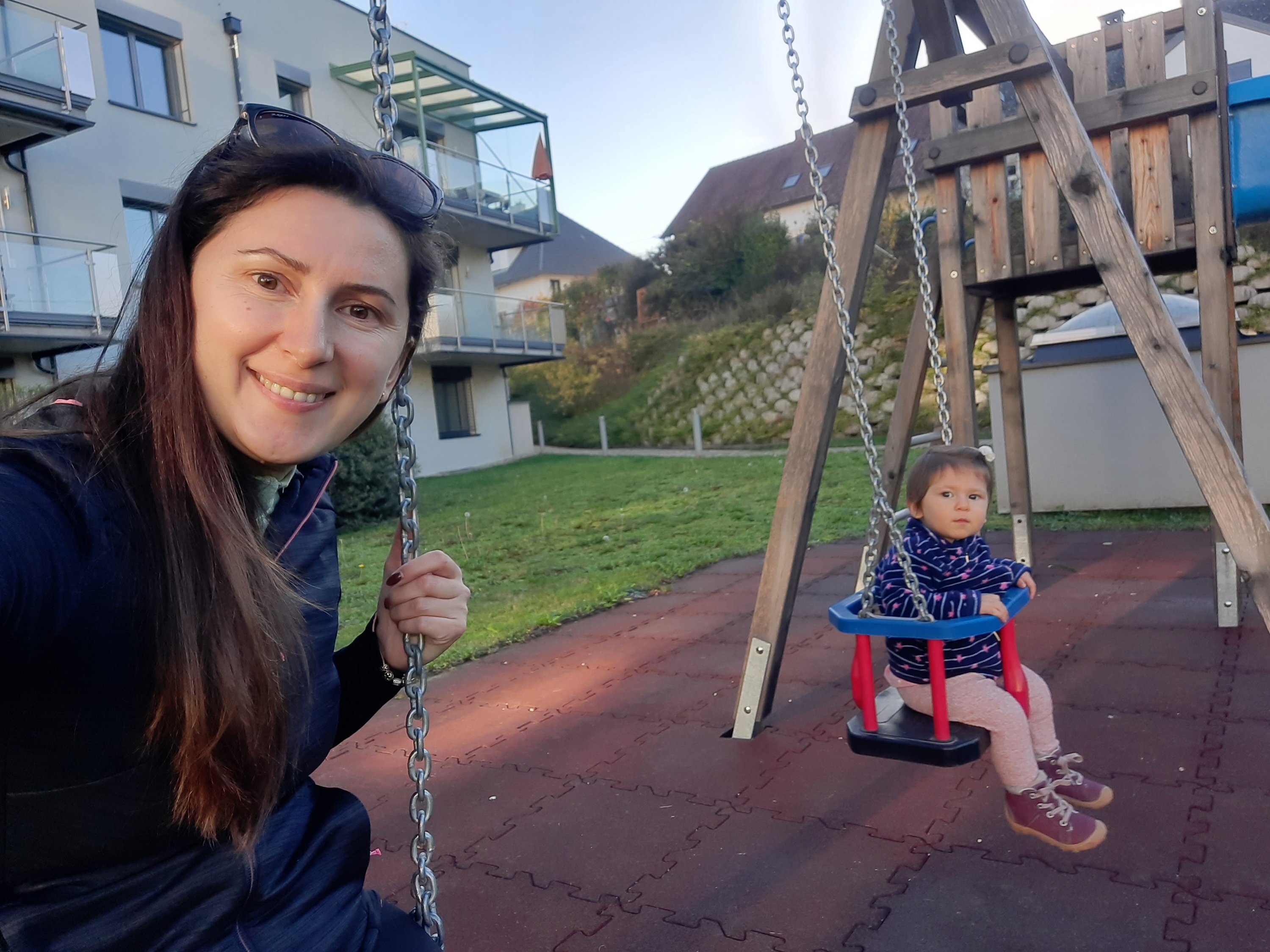 Fjolla and her daughter on a set of swings in front of their home