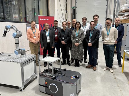 Personen stehen hinter einem Roboter im Labor