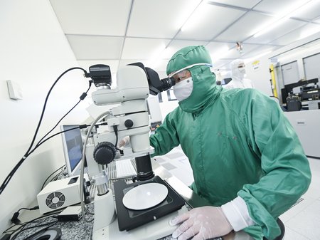 A researcher looking through a microscope in the clean room