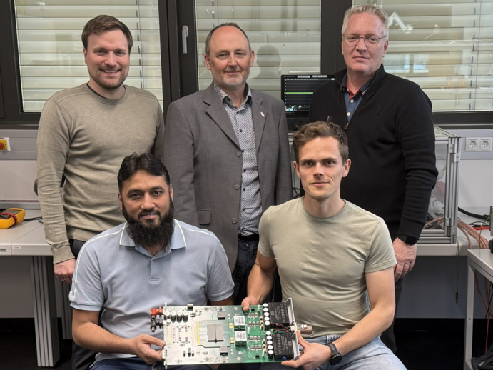 Forscher sitzen im Labor und halten eine Leiterplatte