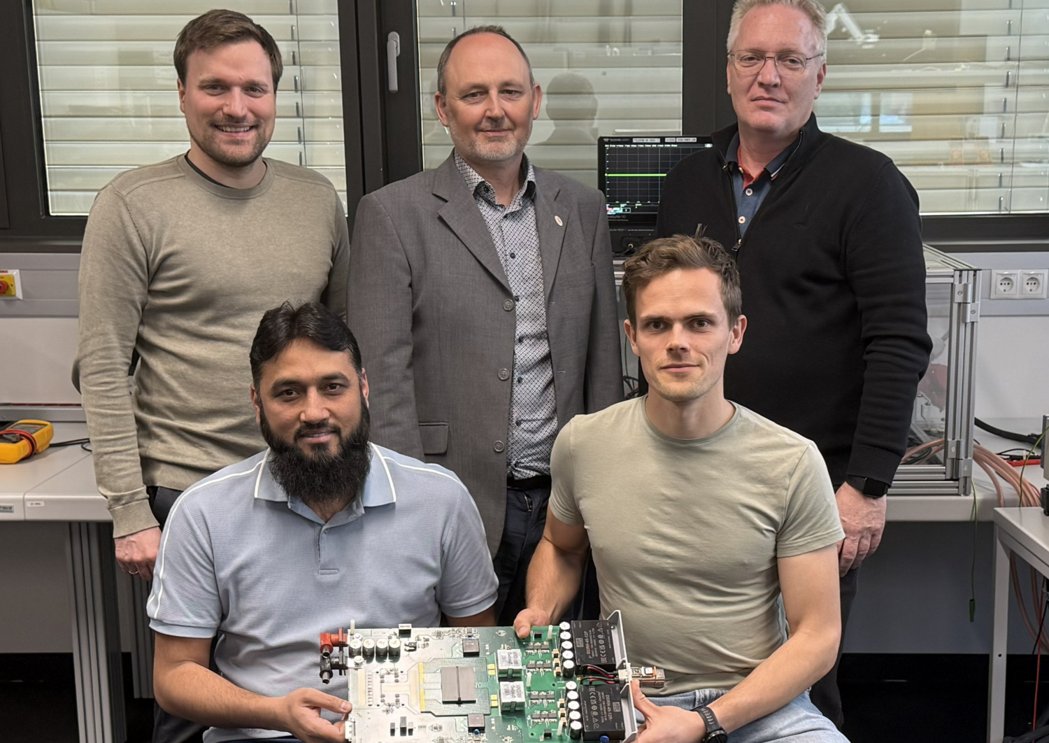 Forscher sitzen im Labor und halten eine Leiterplatte