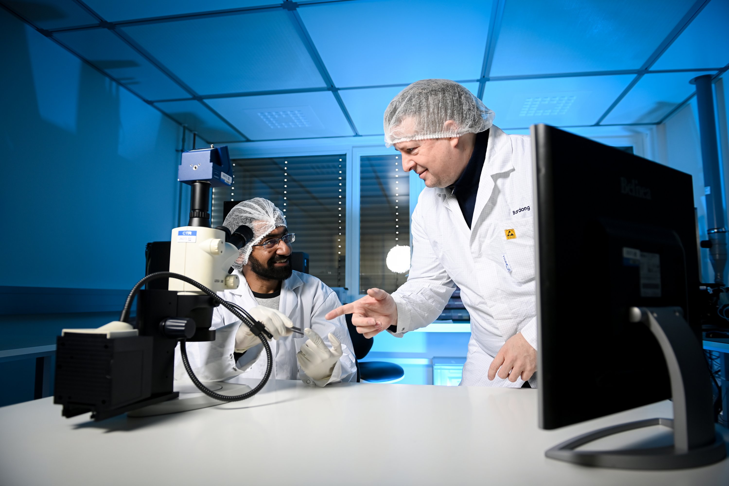 two researchers in the cleanroom, wearing protective clothing