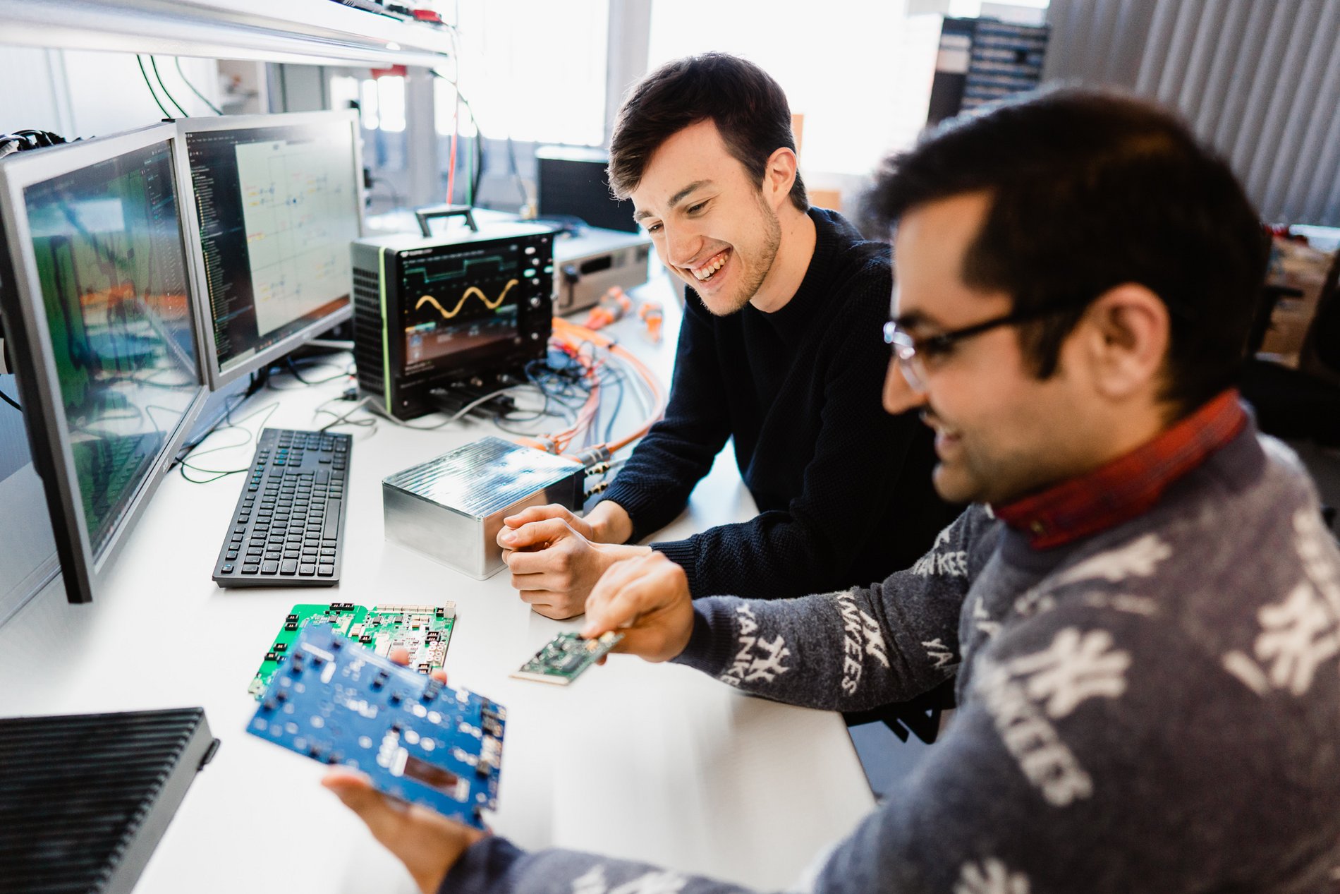 two researchers are looking at a printed circuit board