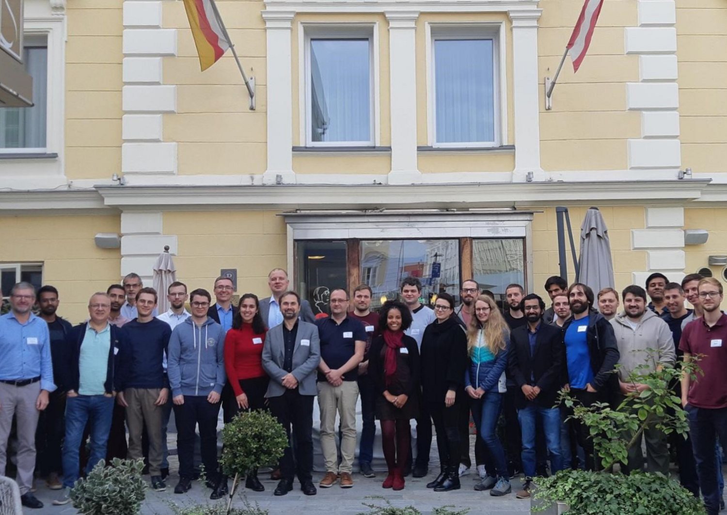 Gruppenfoto von Studiernden und Lehrenden vor einem gelben Gebäude