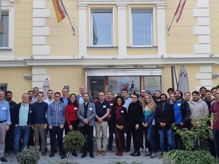 Group picture of students and professors in front of a yellow building