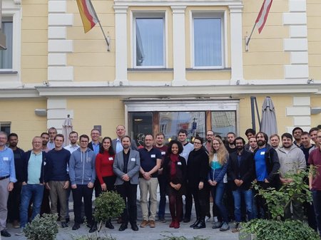 Gruppenfoto von Studiernden und Lehrenden vor einem gelben Gebäude