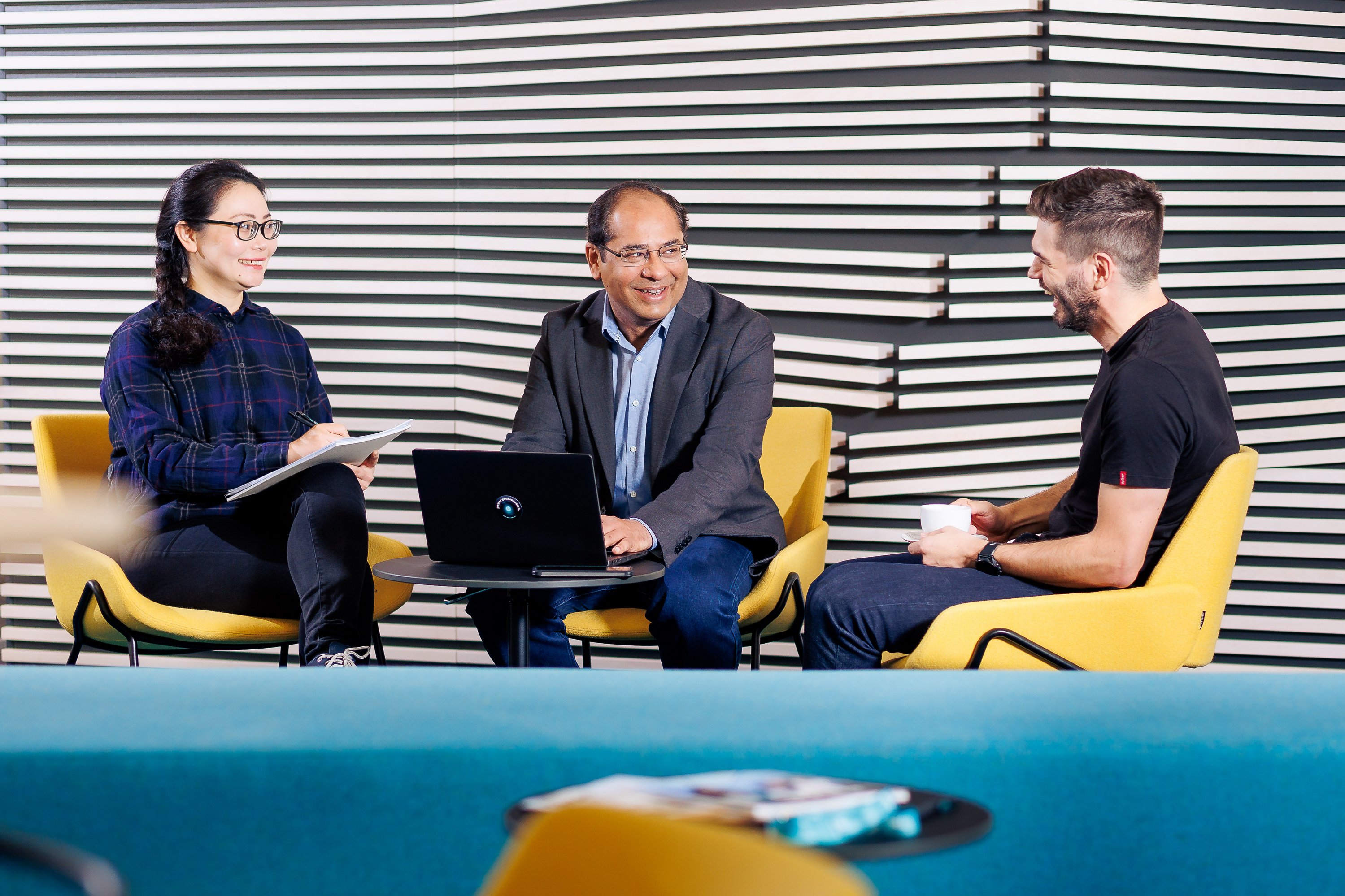 Raheeb and two colleagues sitting around a table, laughing