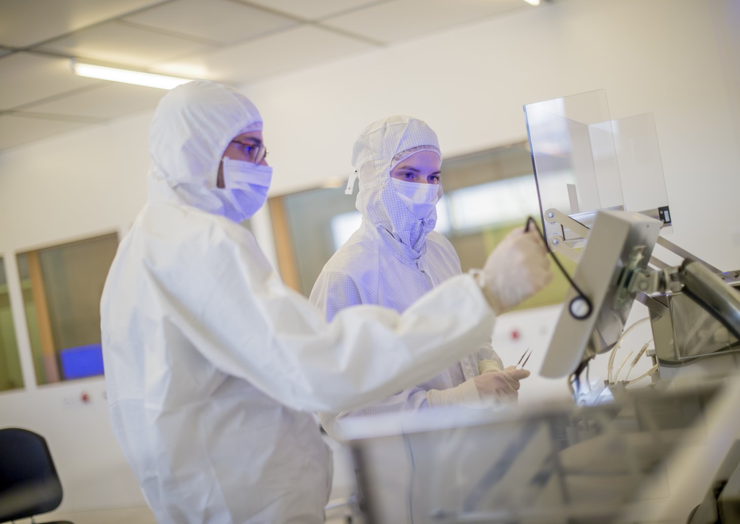 Two scientists working on something in cleanroom clothing in a cleanroom 