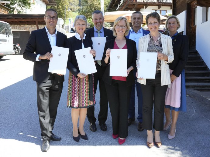 Christoph Ludwig, Gaby Schaunig, Gerald Murauer, Leonore Gewessler, Wilfried Enzenhofer, Sabine Herlitschka and Marion Mitsch, standing side by side with a declaration of continued support for the center of excellence until 2030 in their hands
