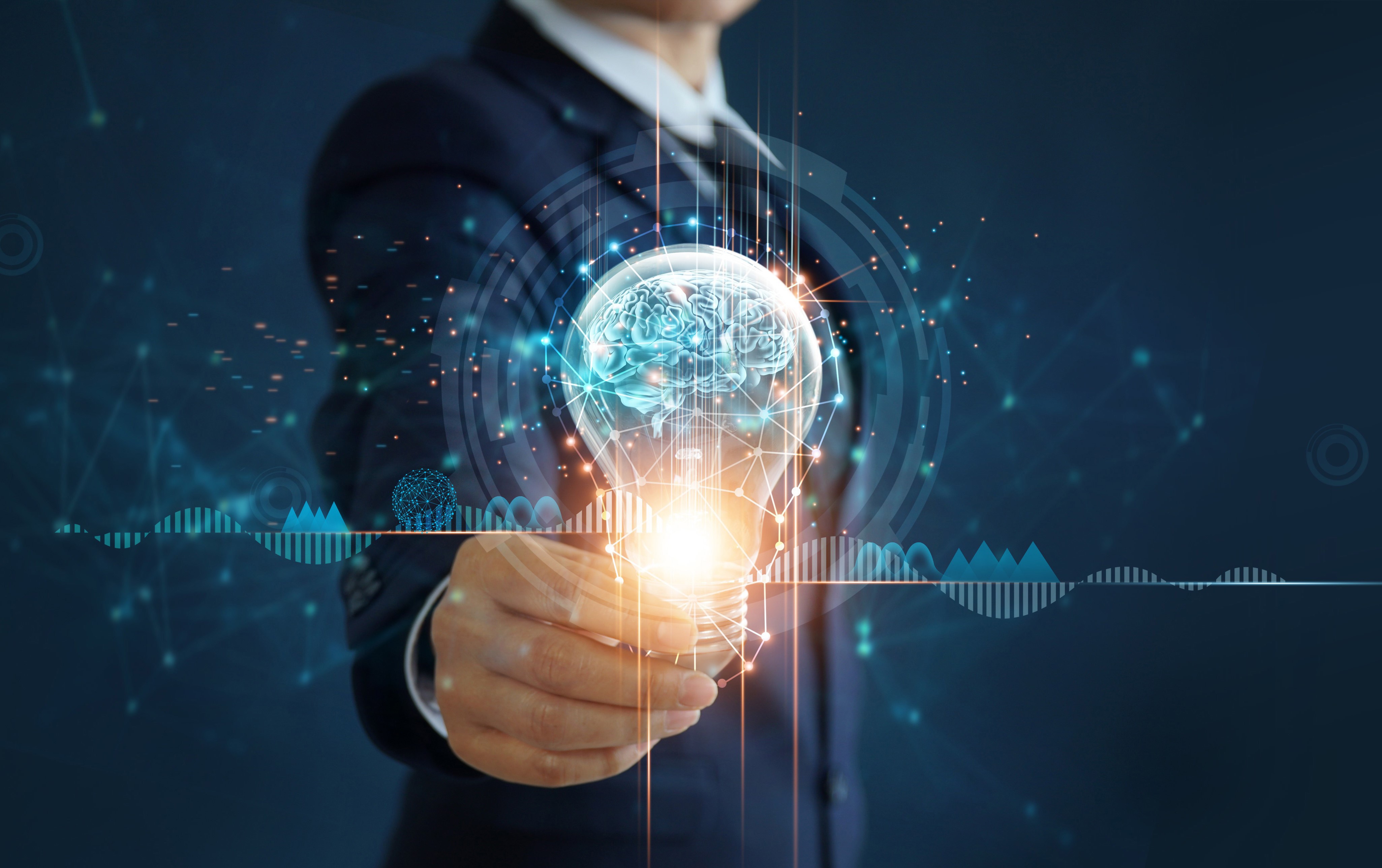 businessman holding illuminated lightbulb with brain inside