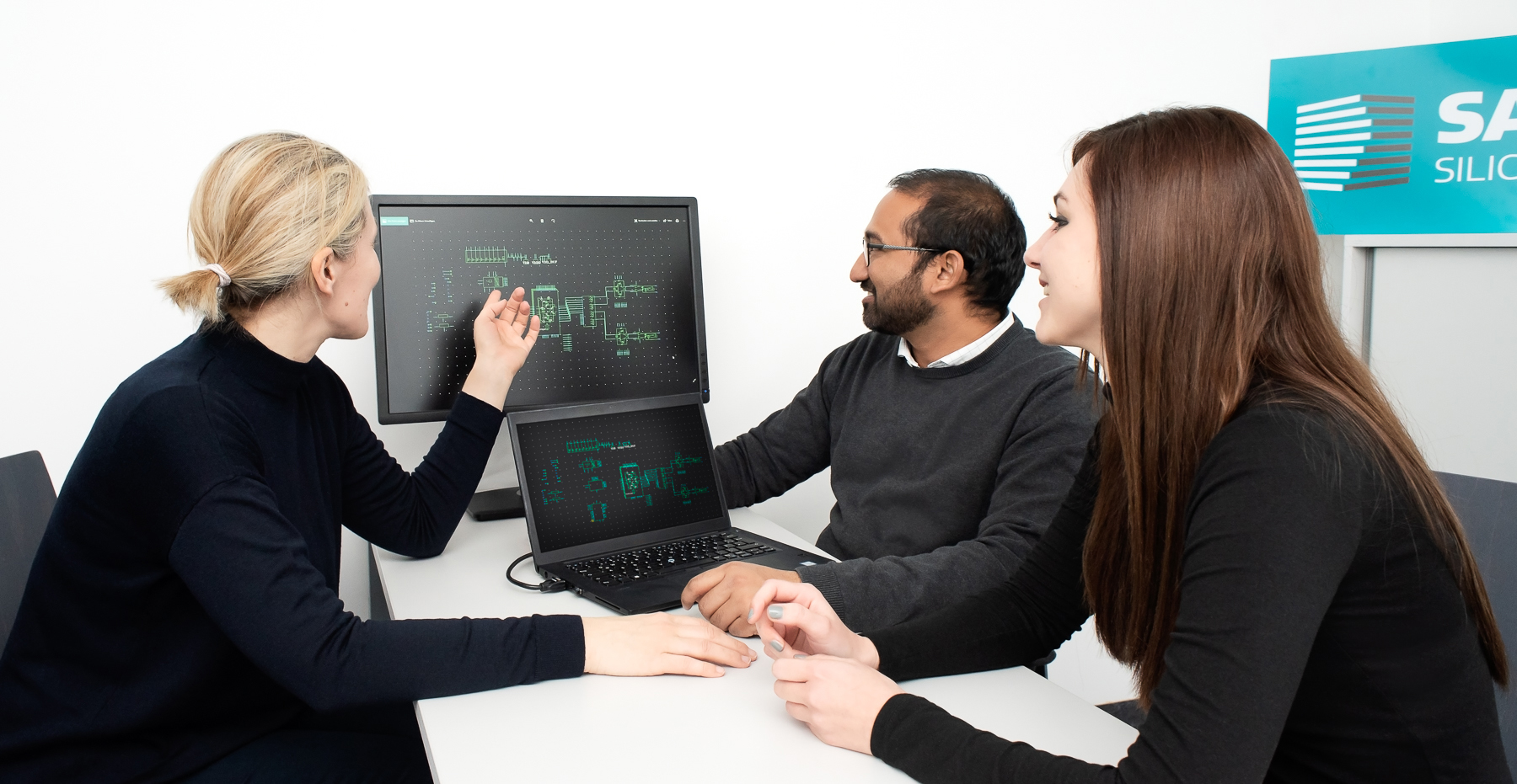 three researchers looking at graphs on a computer screen